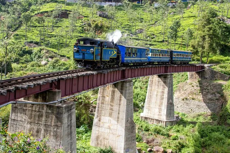 The blue and cream Nilgiri Mountain Railway toy train on the line through the Nilgiris